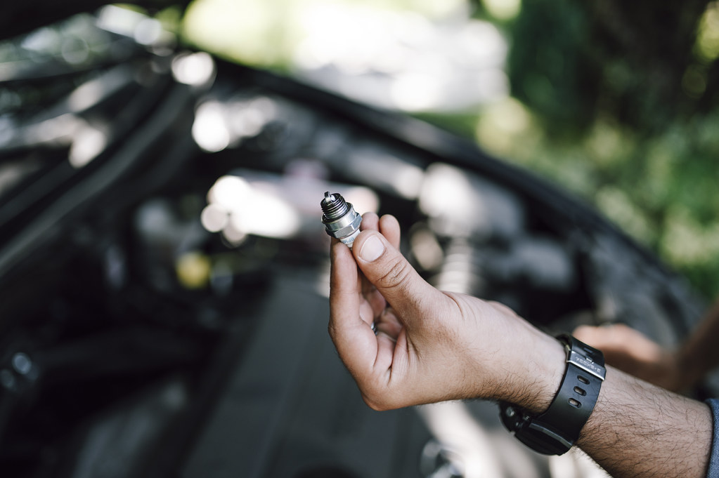 Auto electrician checking a spark plug during an engine diagnostic